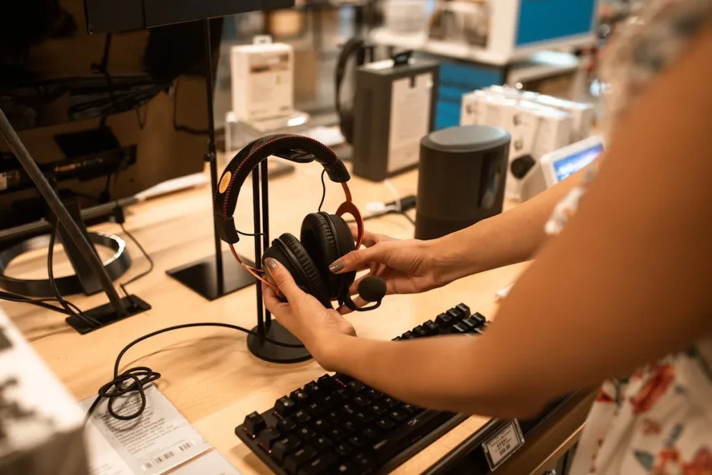Person examining over-ear headphones on display in an electronics store — how to choose headphones guide
