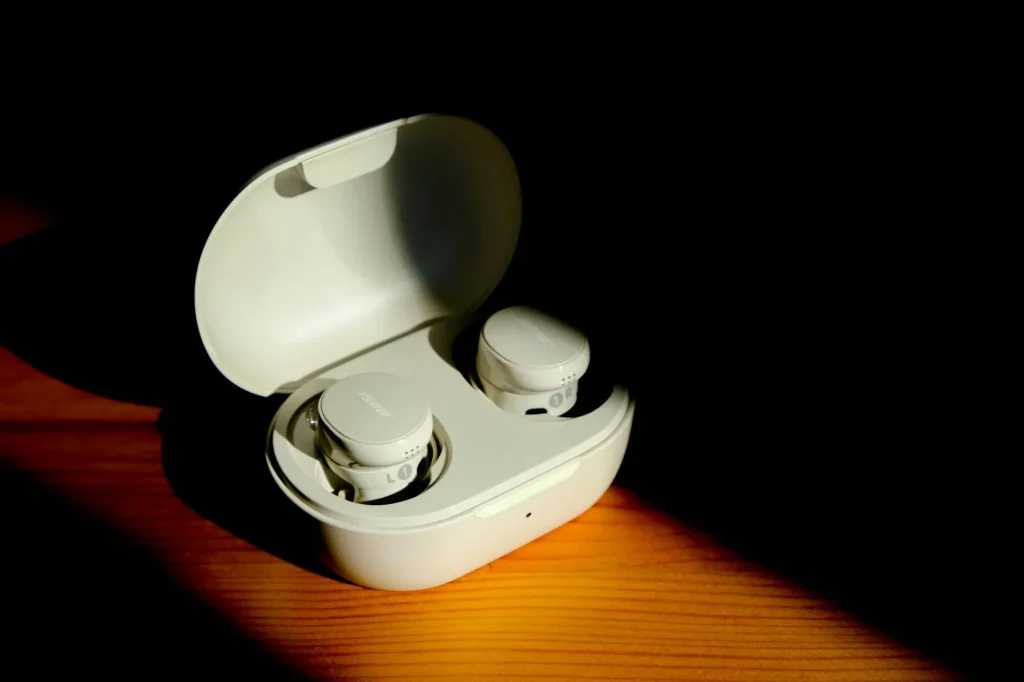 Wireless earbuds and charging case on a desk — best earbuds for small ears UK