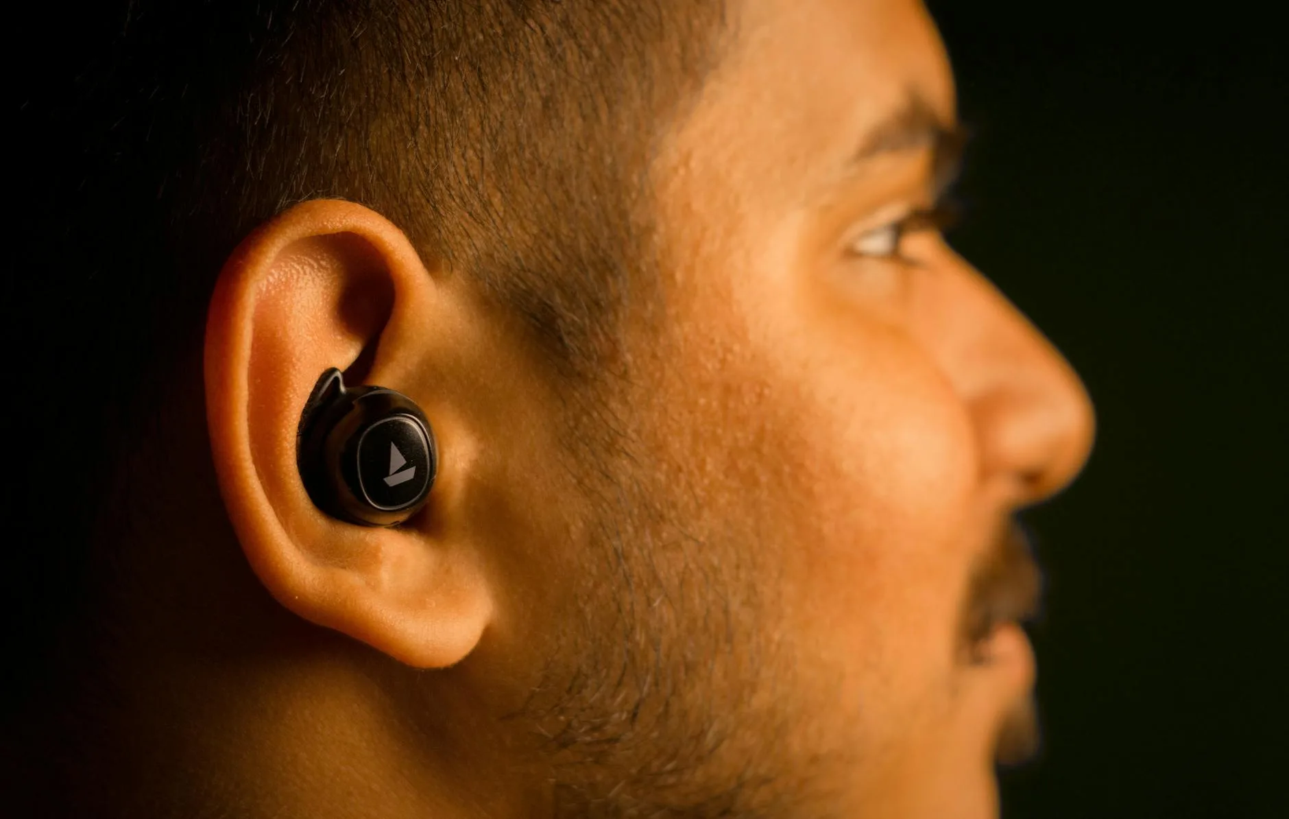 Close-up of a person fitting a wireless earbud into their ear