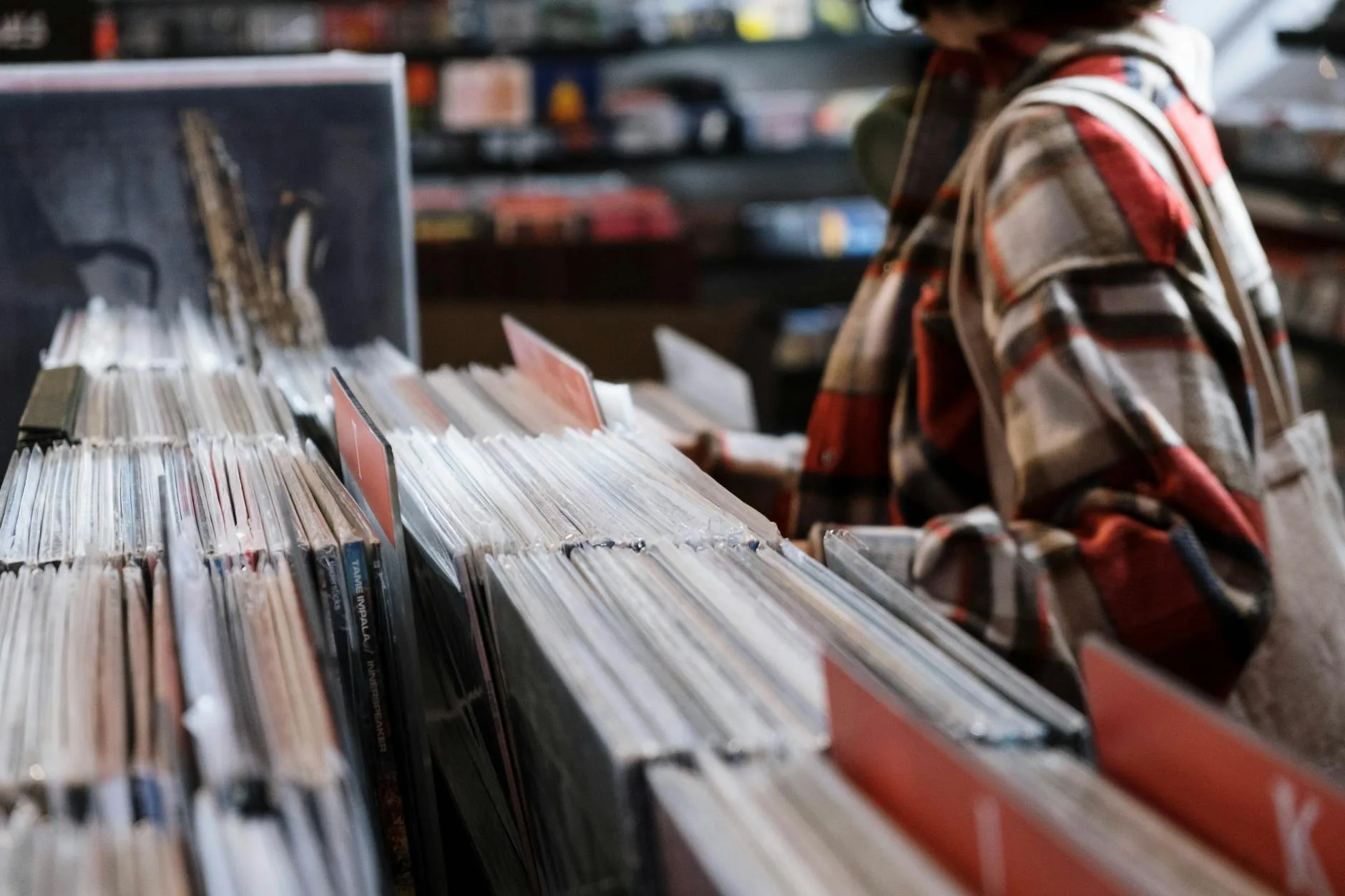 Person browsing through vinyl records in a music shop