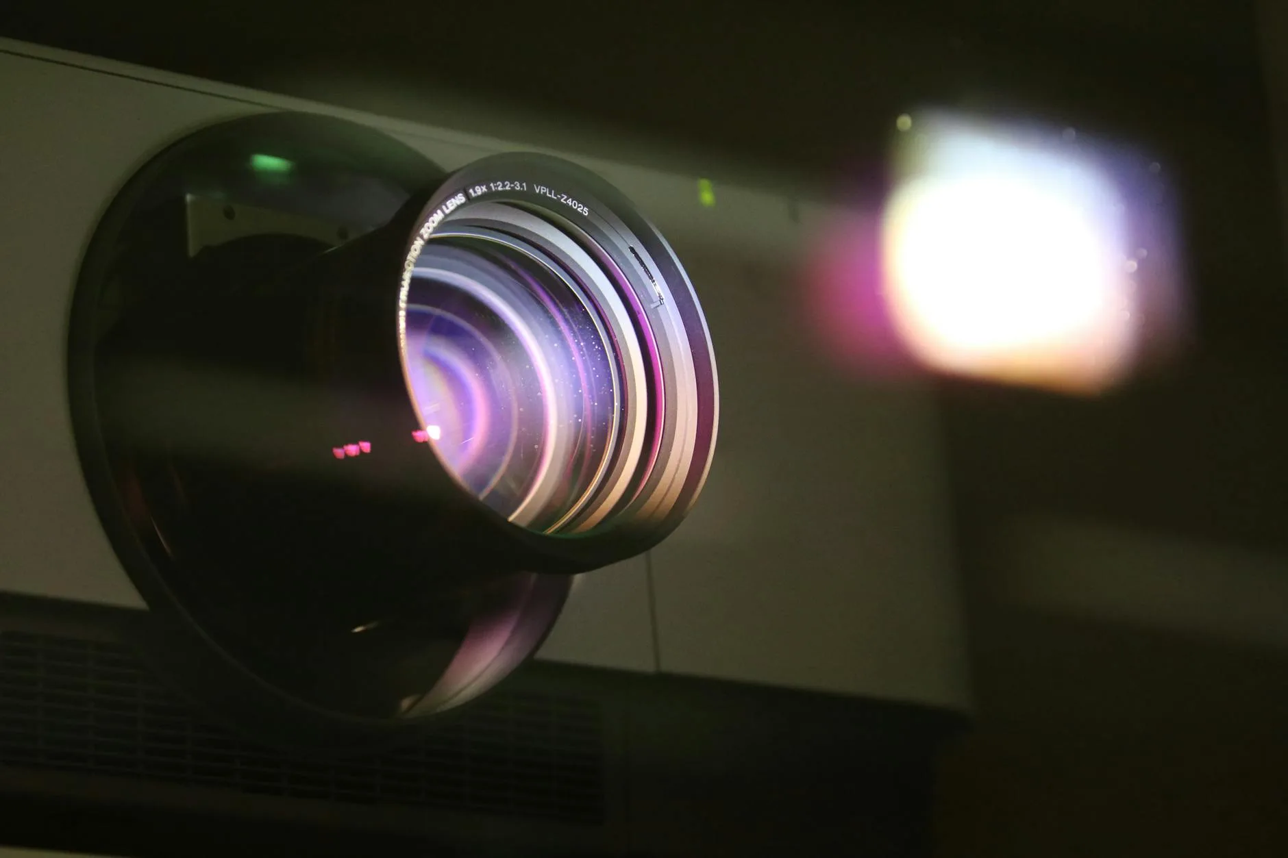 Close-up of a projector lens with light beam in a cinema