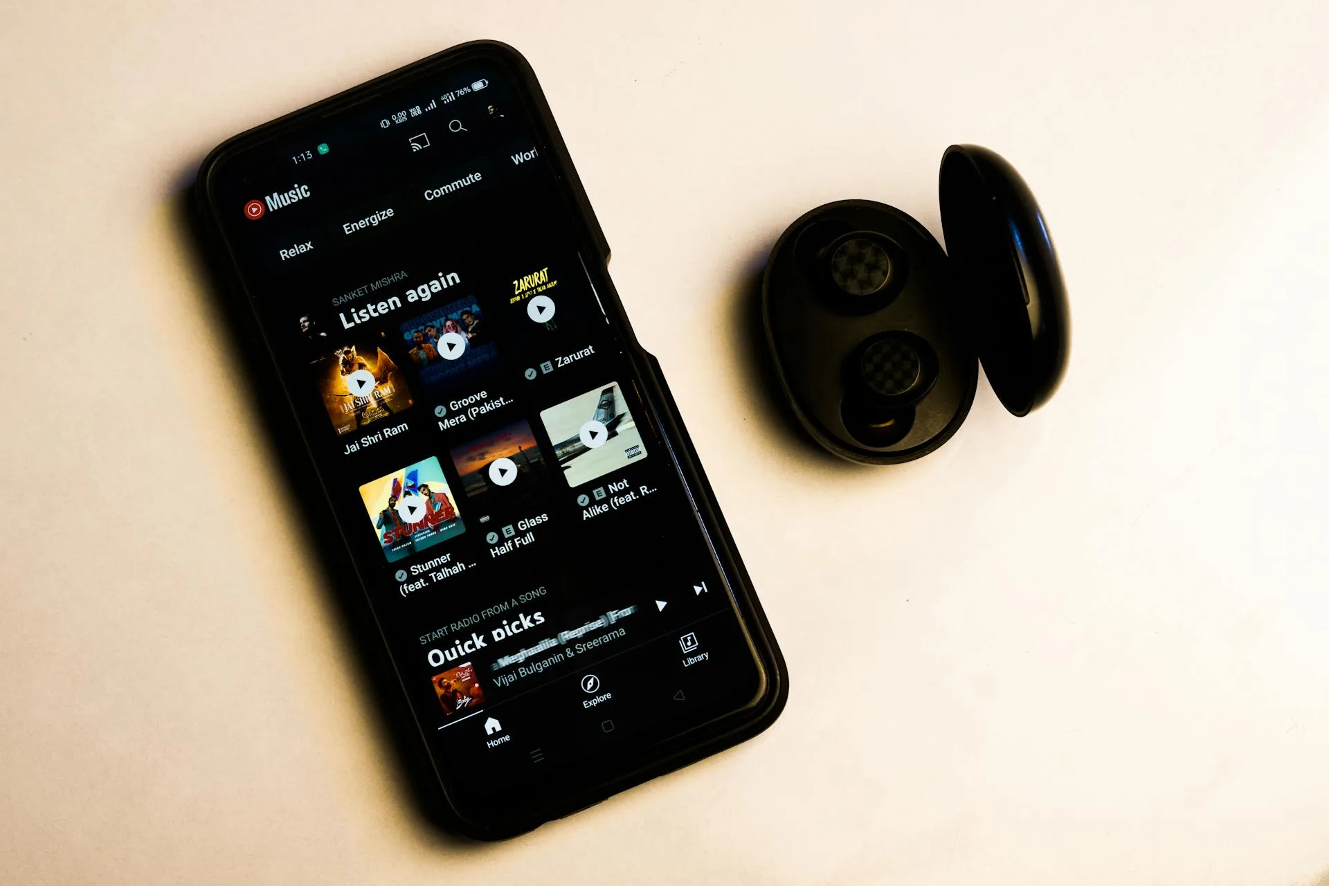 Smartphone displaying a music streaming app with wireless earbuds