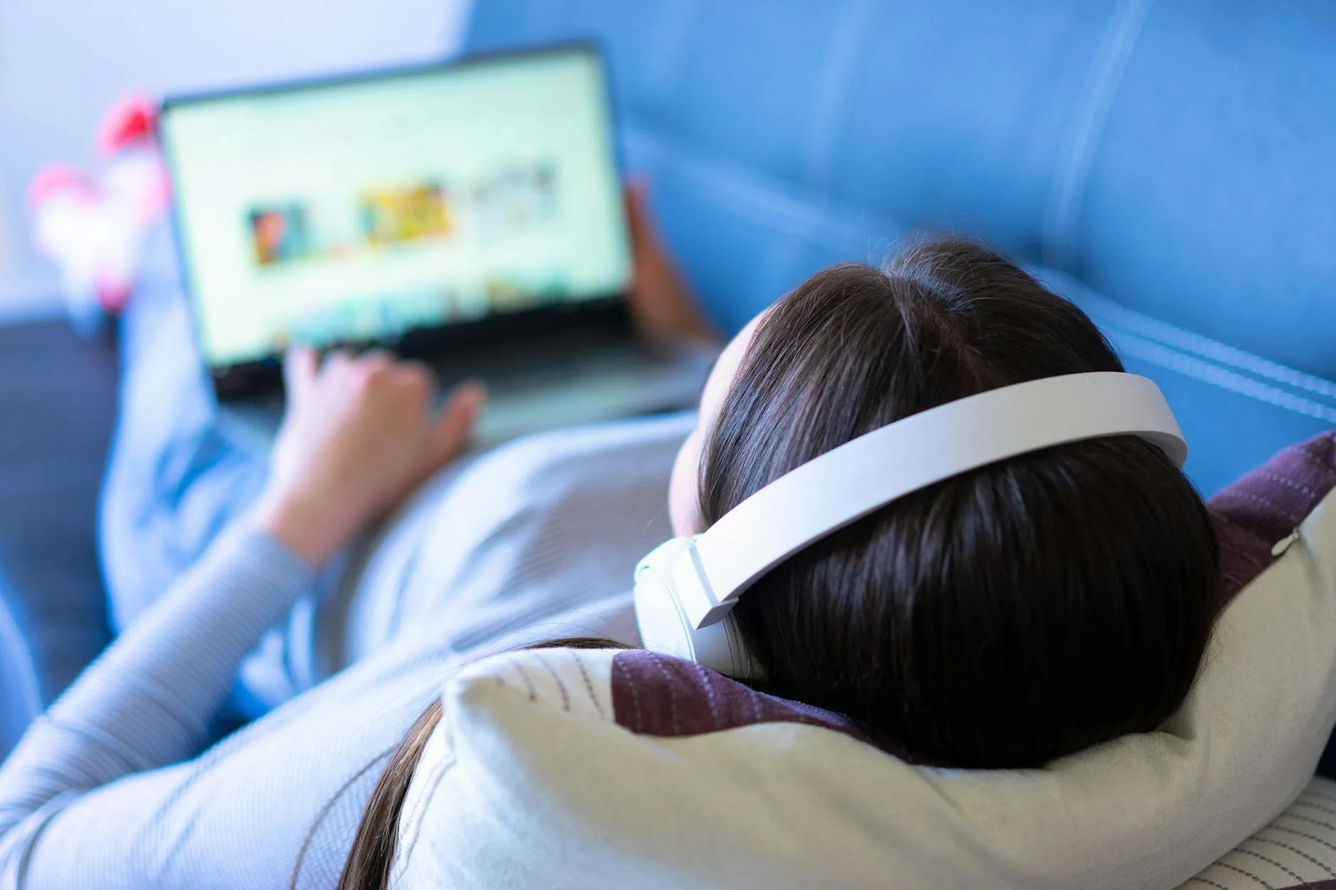 Person relaxing on a sofa listening to music with headphones