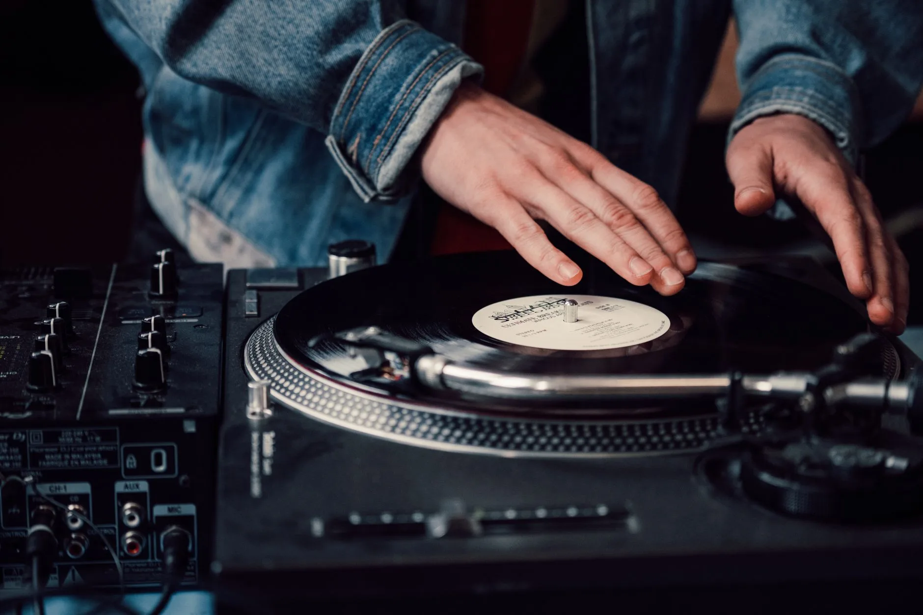 Hands cueing a vinyl record on a turntable before playback