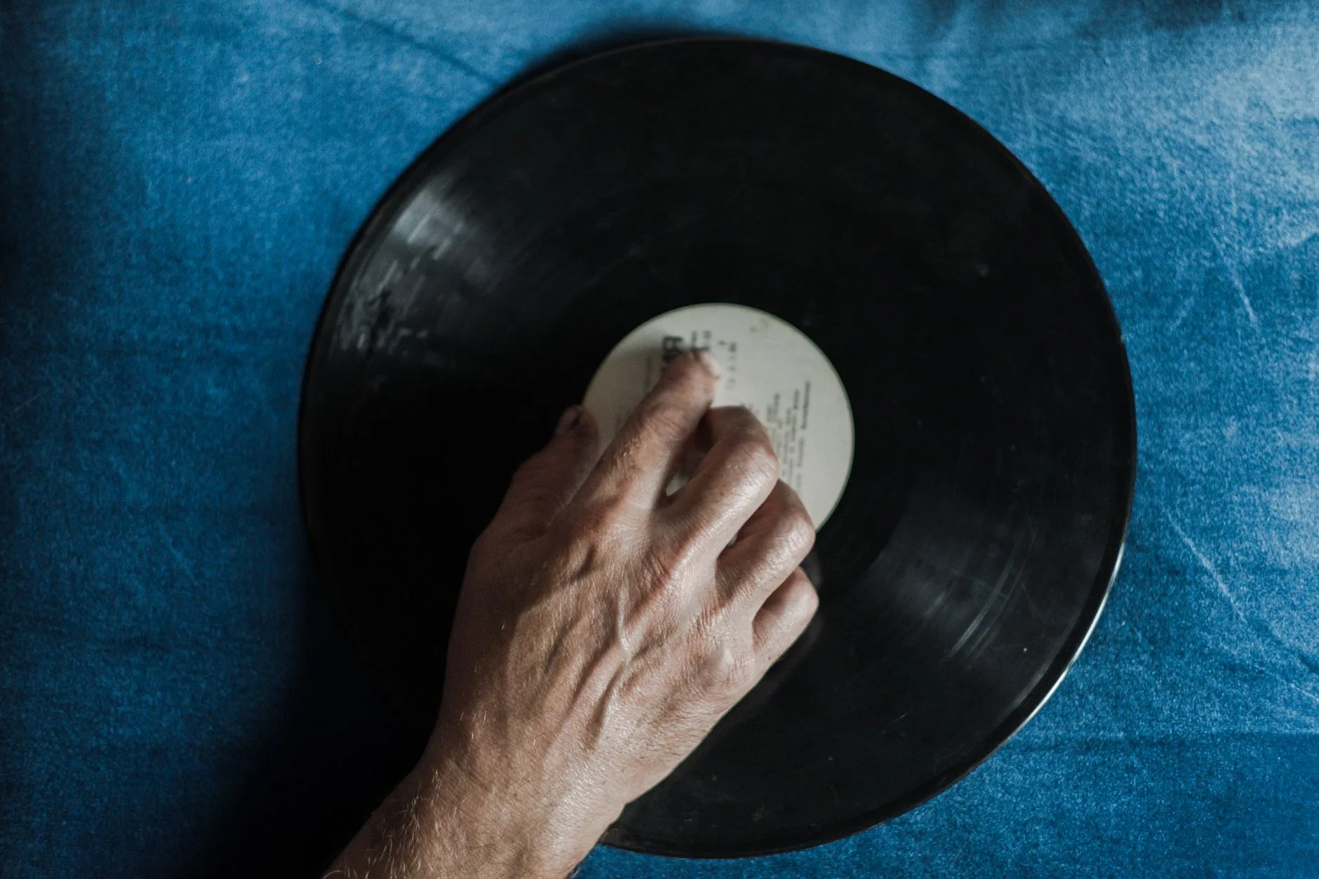 Vinyl record being handled carefully beside a turntable